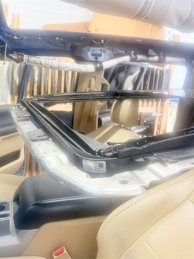 Sunroof opening, frame and mechanism seen from inside a vehicle during panoramic roof repair at the Sunroof King shop in Houston