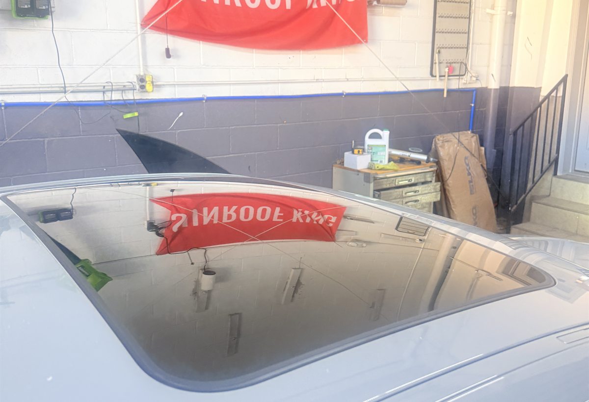 Finished custom sunroof glass panel closed flush in a light vehicle roof inside the Sunroof King Houston shop
