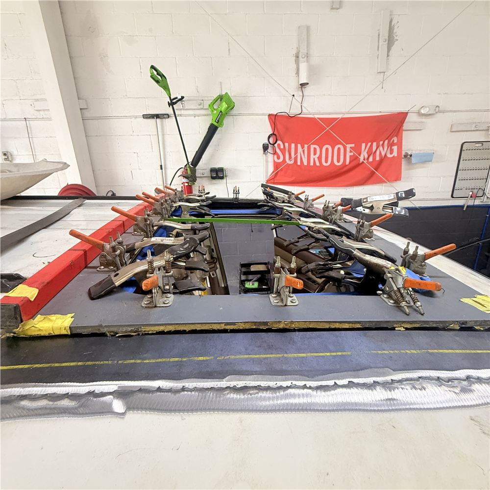 Roof panel clamped in a jig during a custom sunroof installation at Sunroof King