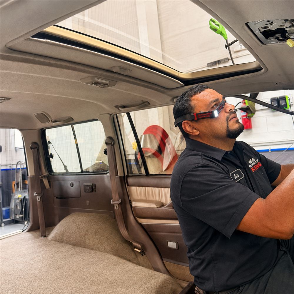 Sunroof King technician inspecting a sunroof and headliner from inside a vehicle