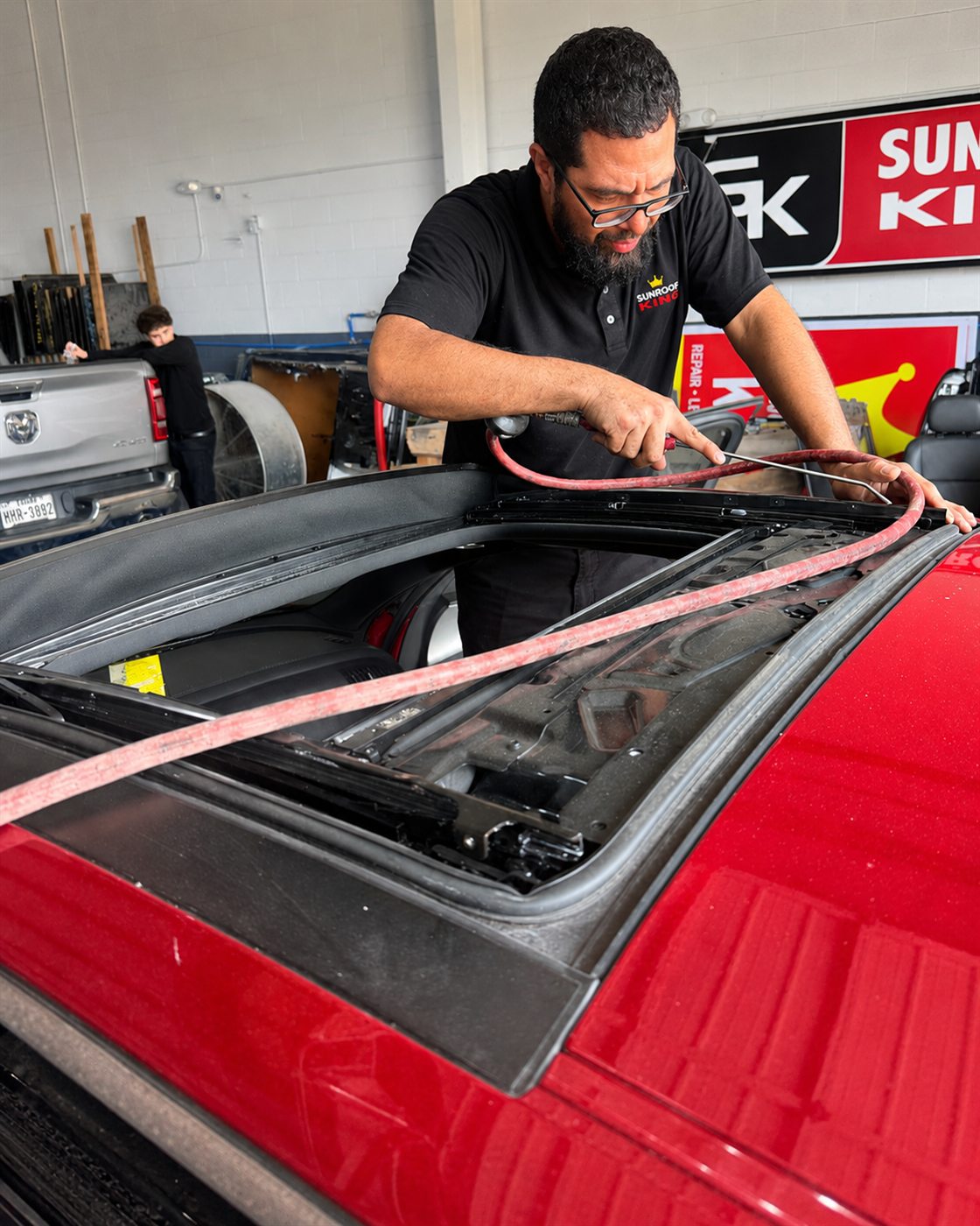 Sunroof King technician sealing a replacement sunroof glass panel on a customer's truck