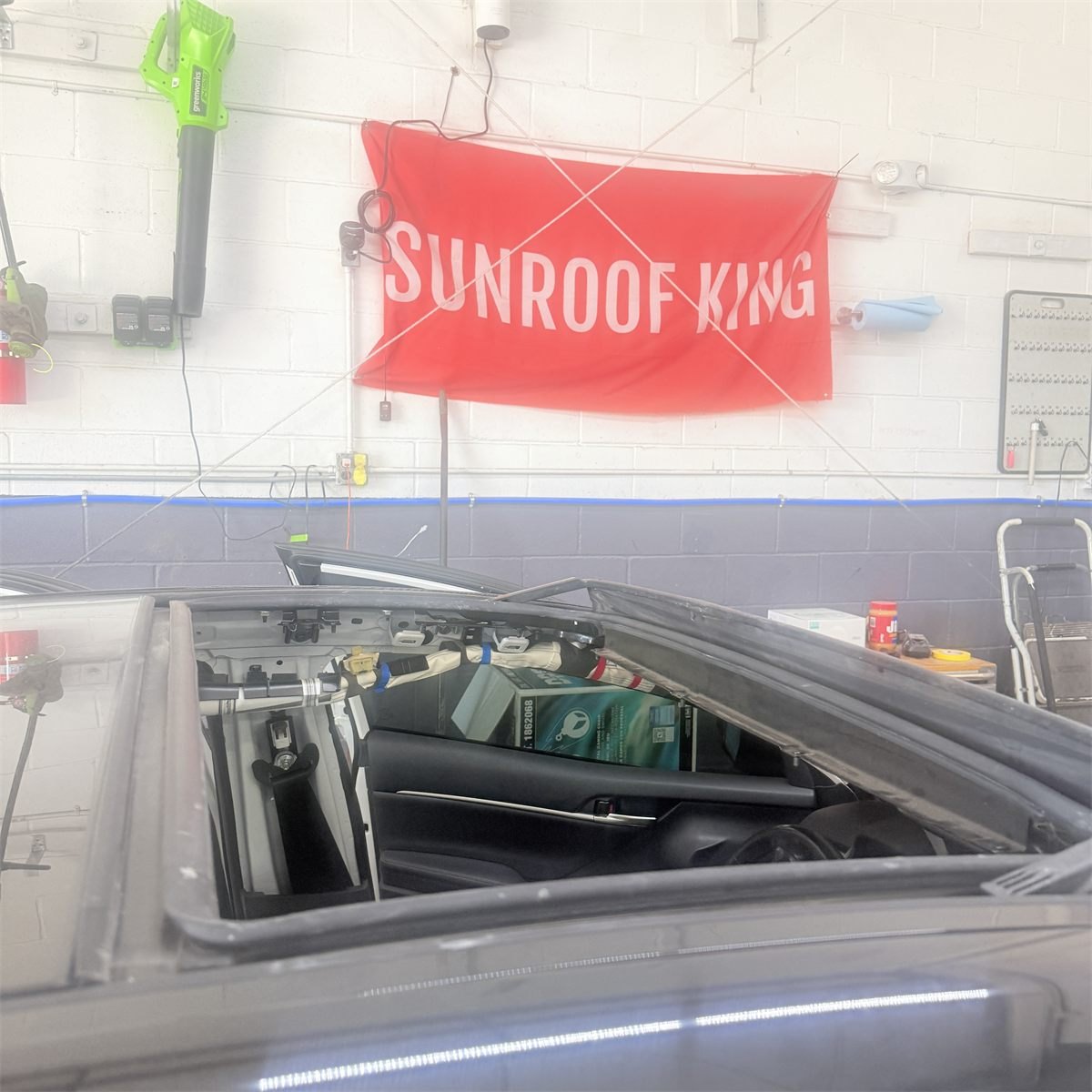 Roof opening with the glass panel lifted clear at Sunroof King, showing the frame and seal channel below