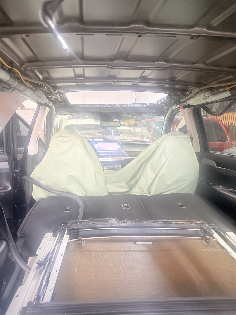 Vehicle interior at Sunroof King in Houston with the headliner removed and the seats covered, exposing the roof structure and sunroof frame
