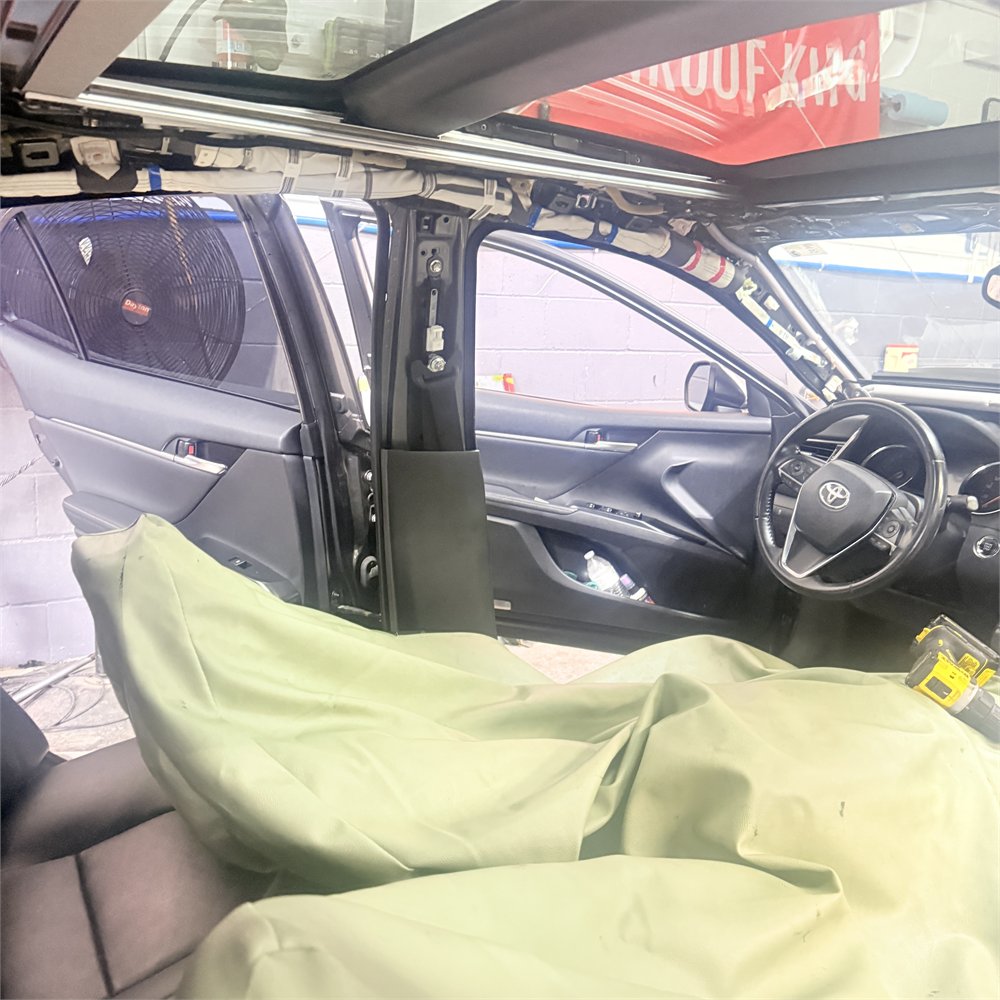 Vehicle interior at Sunroof King in Houston with protective covers over the seats and the pillar trim removed during sunroof leak work