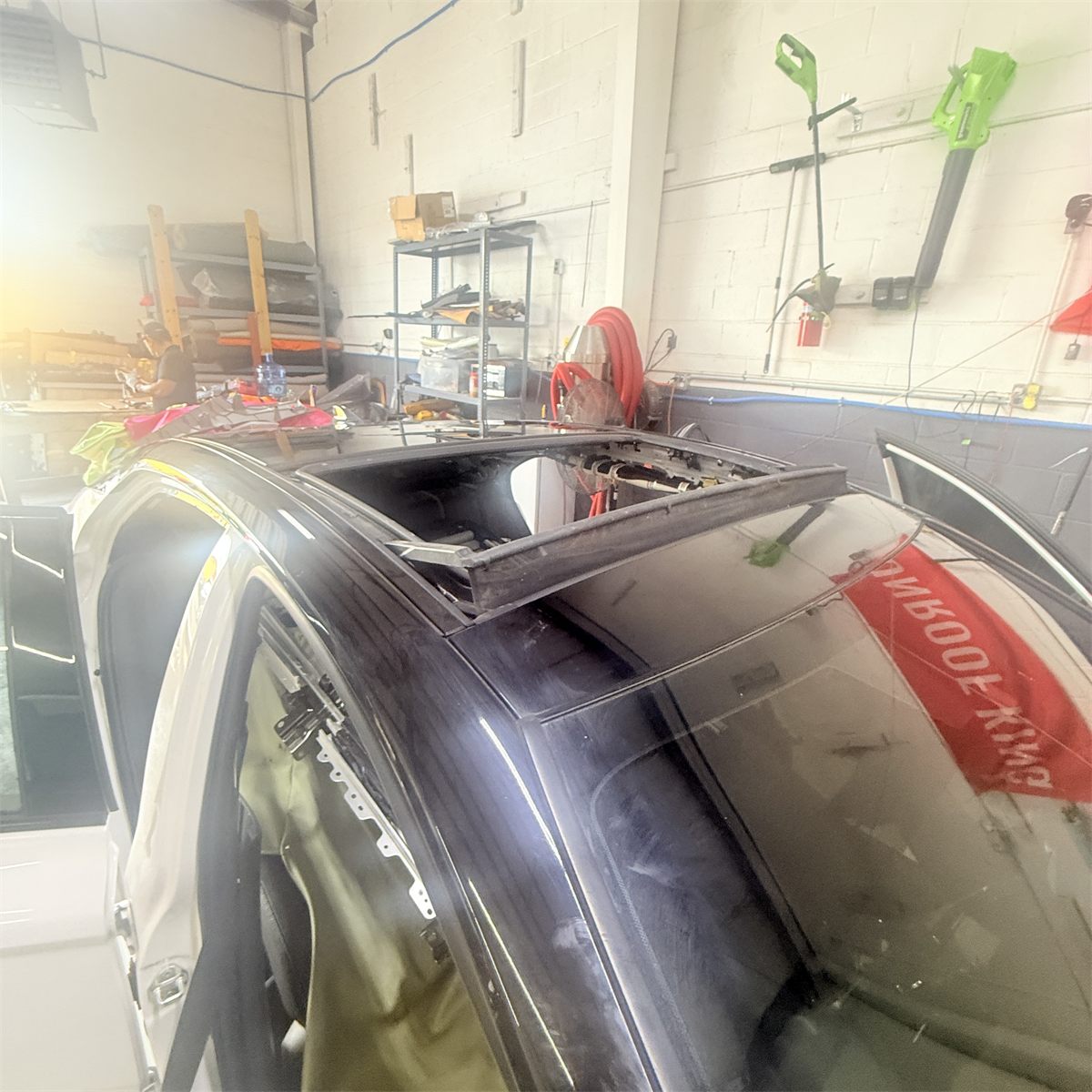 Sunroof glass panel raised off a car roof at the Sunroof King shop in Houston, exposing the guide tracks and mechanism underneath