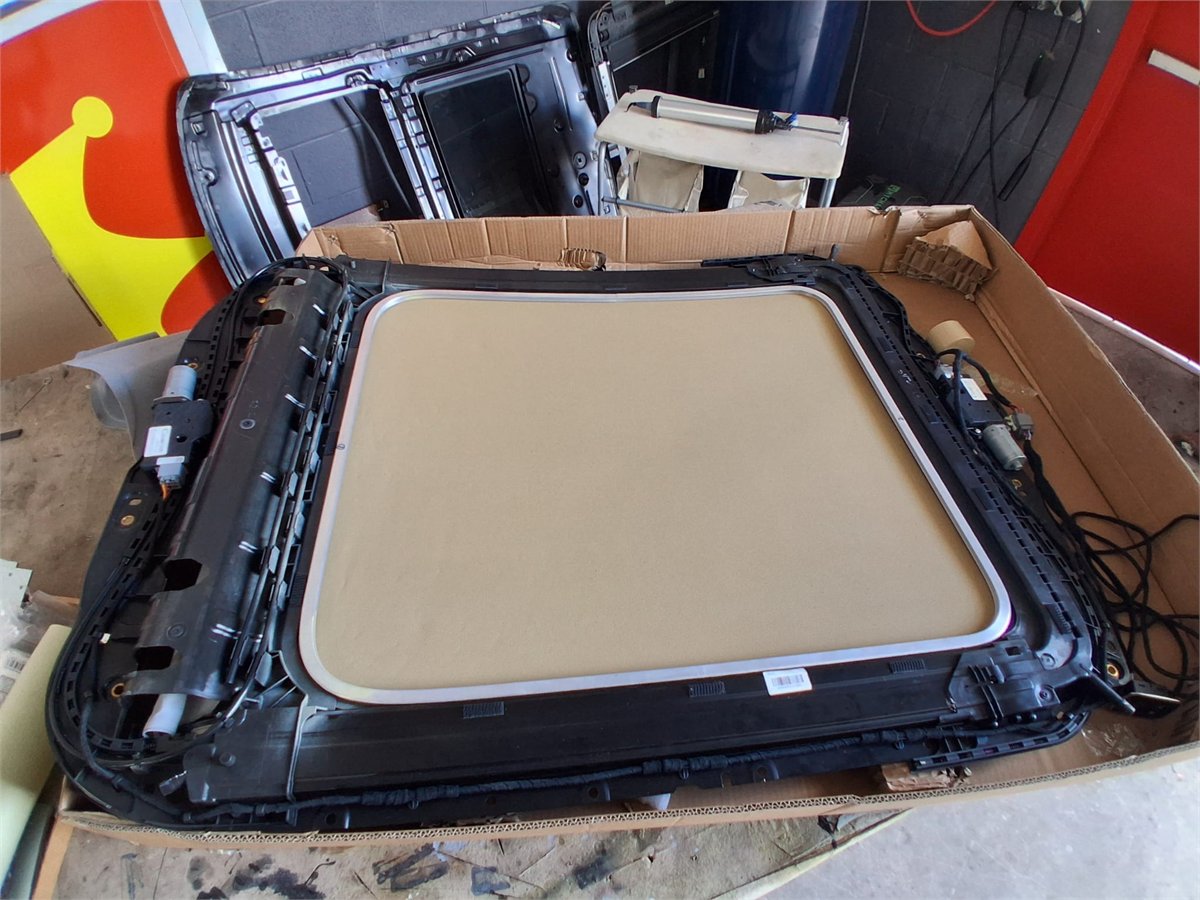 Complete panoramic sunroof cassette and shade assembly removed from a vehicle at Sunroof King in Houston, showing the shade in its frame