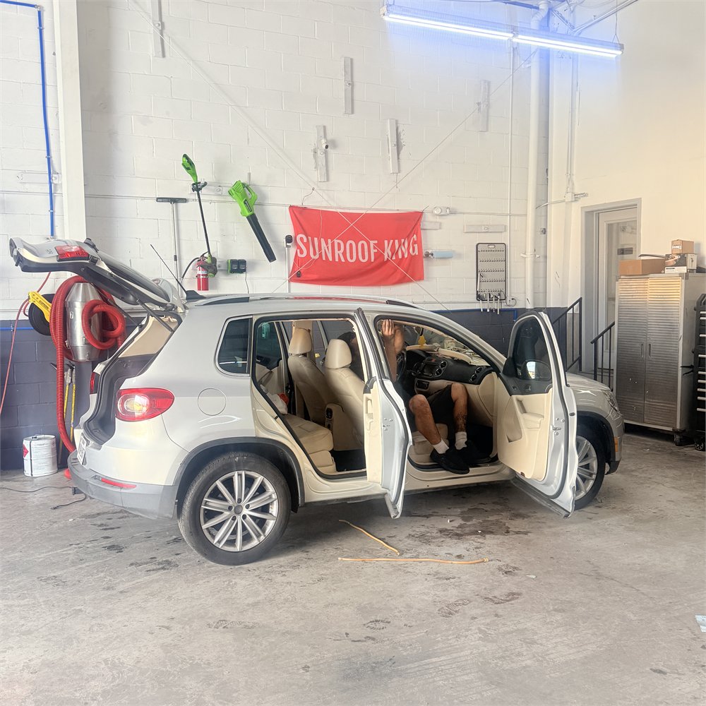 SUV in the Sunroof King bay in Houston with its doors open and interior partly dismantled during a sunroof shade repair