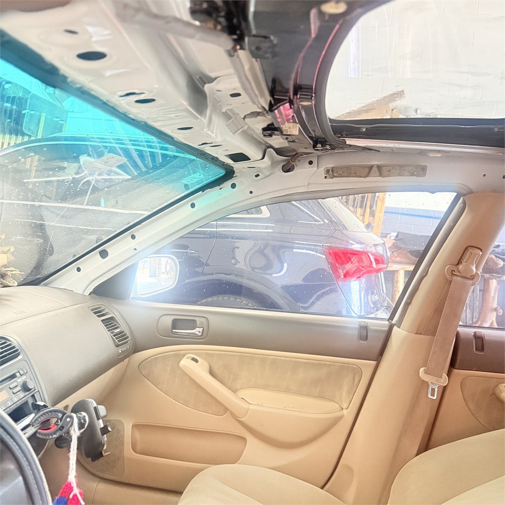 Headliner removed inside a vehicle at Sunroof King in Houston, exposing the bare roof structure and the sunroof frame above