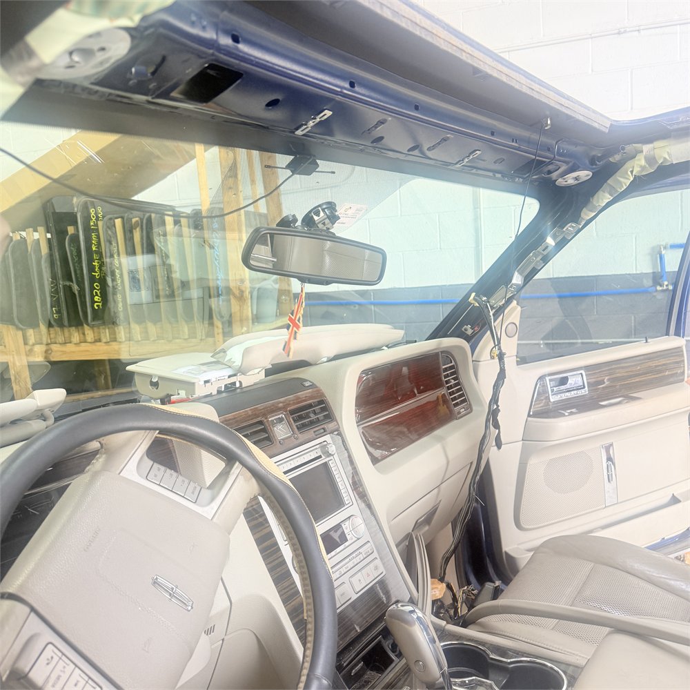 Vehicle with the front of the headliner lowered at Sunroof King in Houston, exposing the roof structure above the windshield