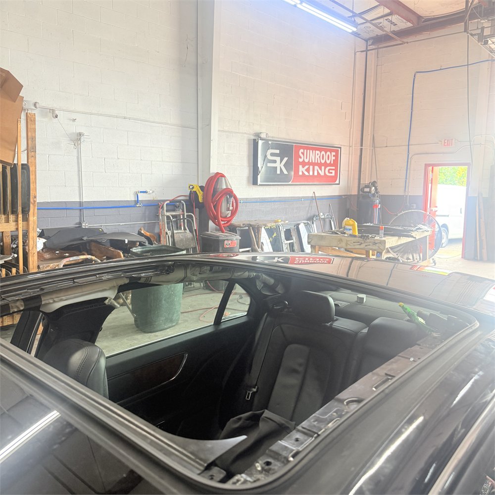 Vehicle in the Sunroof King shop in Houston with the sunroof panel fully open, seen from above the roof line