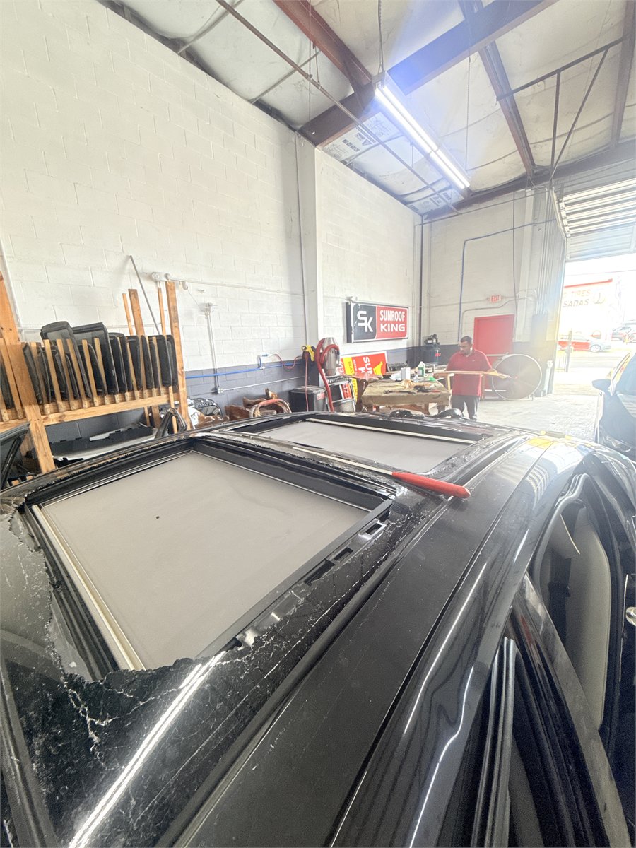 Close-up of a sunroof opening with the glass removed, showing the rails and frame around the aperture at the Sunroof King shop in Houston