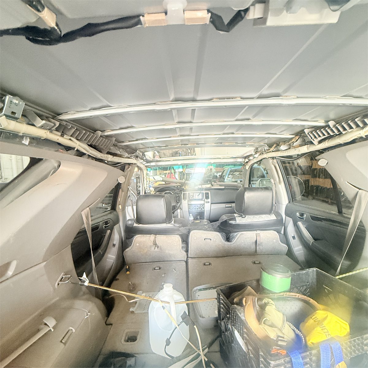 Interior of an SUV at Sunroof King in Houston with the headliner lowered, exposing the roof structure, wiring and the sunroof opening above the seats