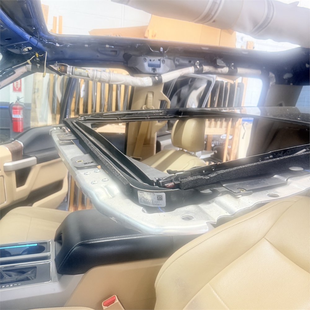 Vehicle interior at Sunroof King in Houston with the headliner removed, exposing the roof structure and the sunroof frame and rails from inside