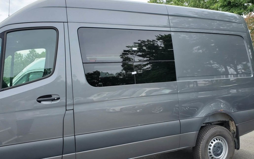 Tinted side window fitted into the panel of a grey Mercedes-Benz Sprinter van